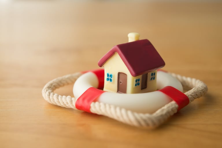 Cute house model is in lifebuoy on wooden table background, property insurance concept