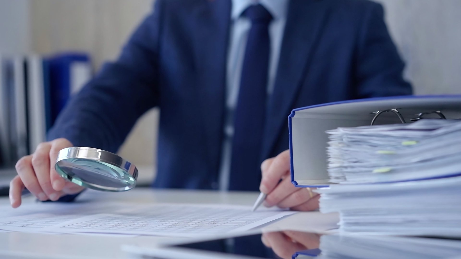 Businessman examining financial documents with magnifying glass for audit analysis