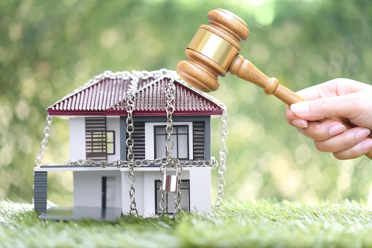 Woman hand holding gavel with locked house with padlock and chain, property auction concept