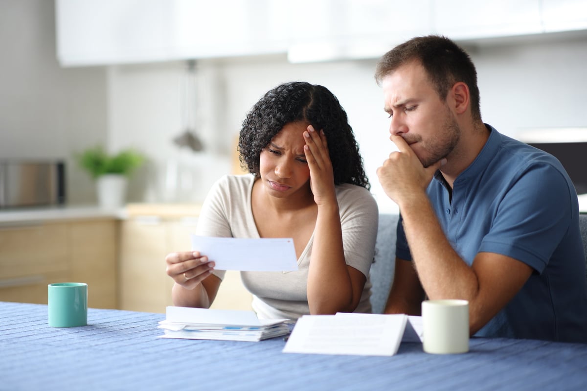 Sad couple checking bank statement together