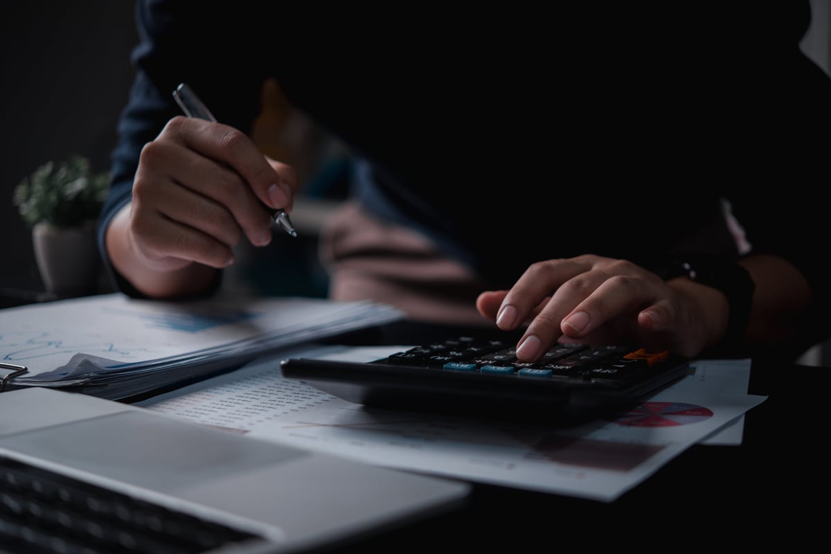 Businessman using calculator for bookkeeping, payroll and budget tax, with business document finance accounting investment