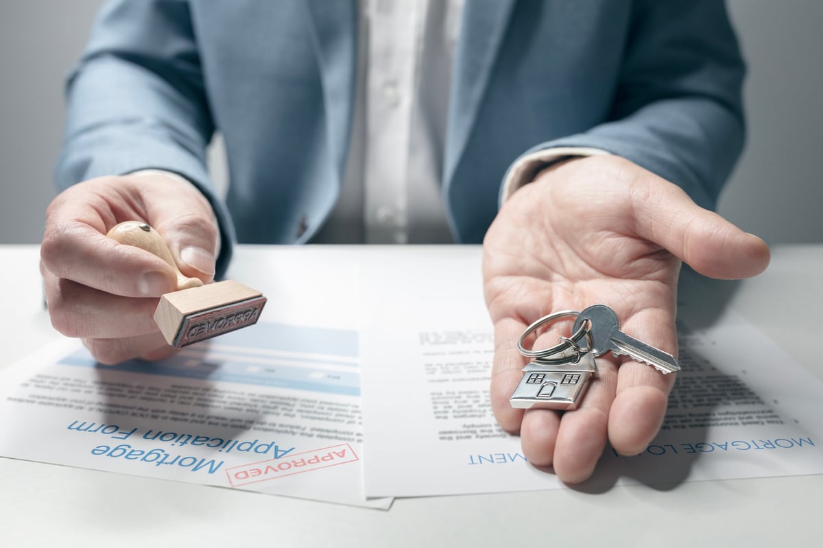 Real estate agent handing over house keys with approved mortgage application form
