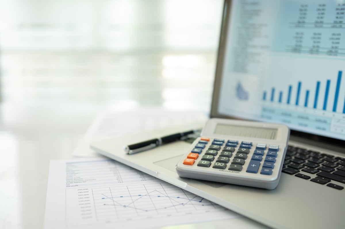 Calculator, account statement and business report with financial budget portfolio showing on a laptop screen, accounting business concept