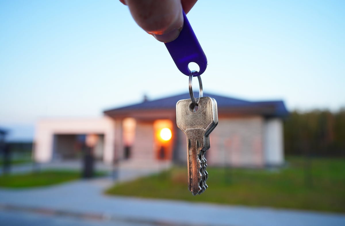 Hand of a real estate agent showing keys of a new house, concept of buying a suburb home or villa