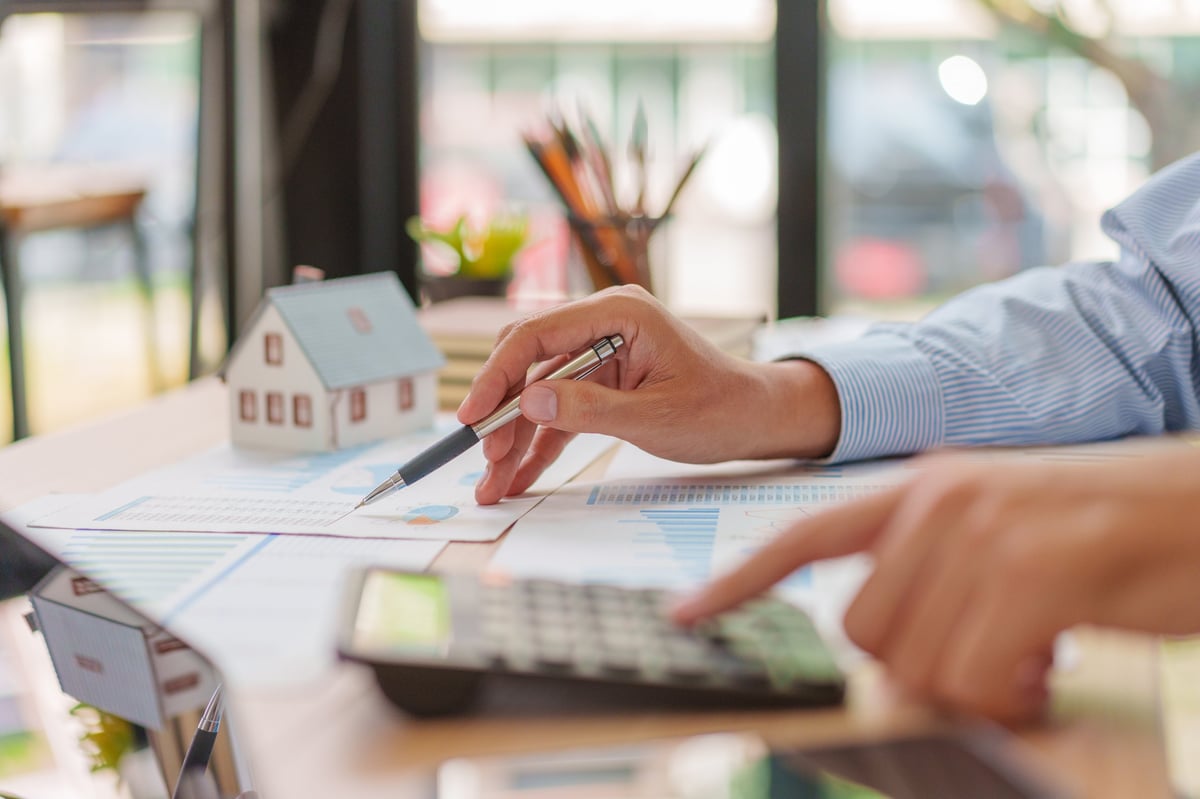 Professional analyzing property market charts and mortgage documents with calculator