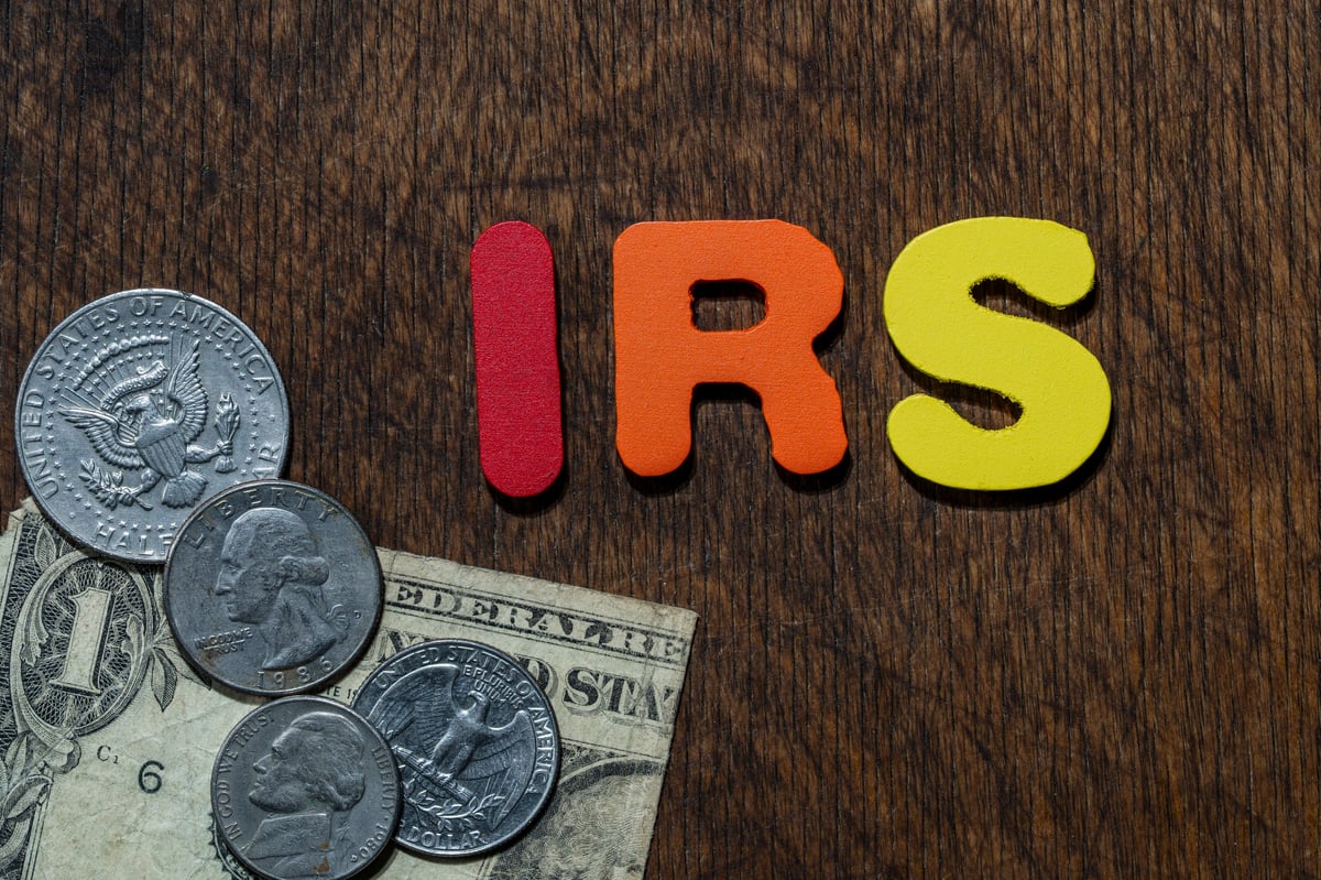 IRS letters with US dollars and coins on wooden background representing taxation and the financial system in the United States