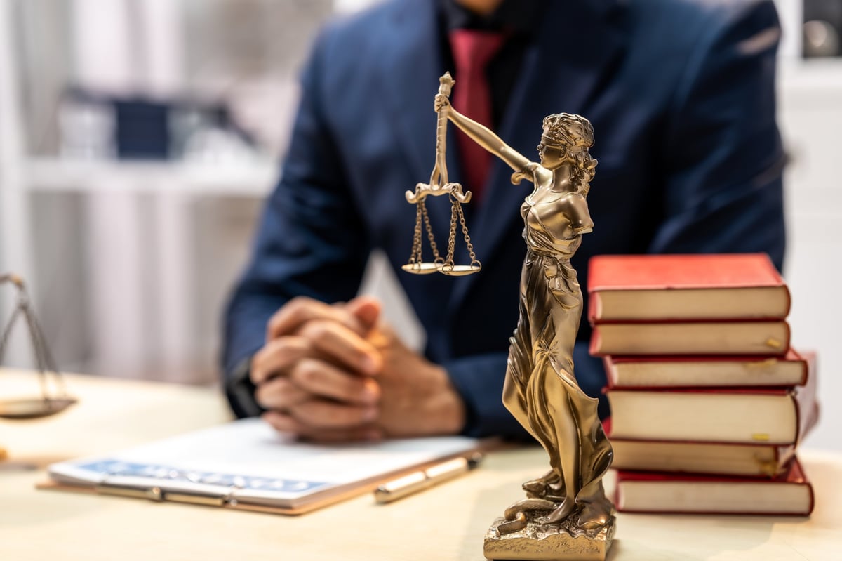 Lawyer office desk with justice statue, scales, legal books and laptop showing professional legal advice