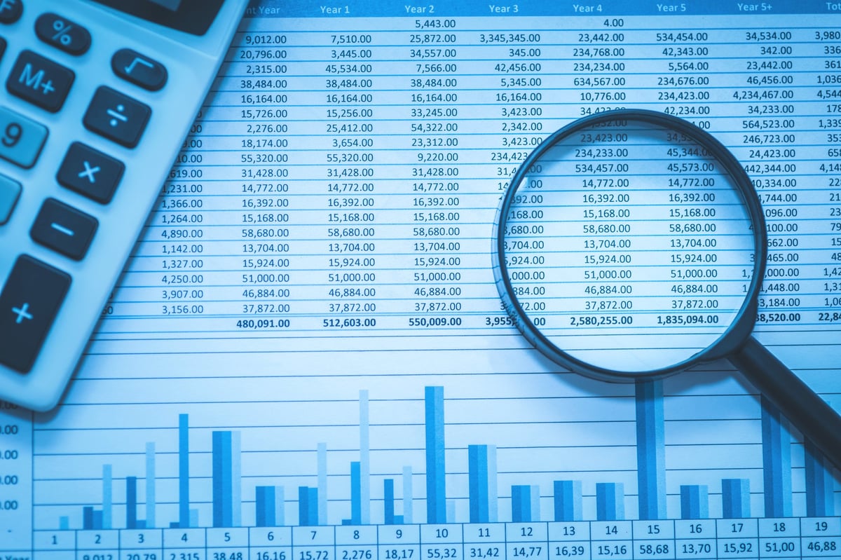 Spreadsheet of bank accounts and accounting with calculator and magnifying glass, concept for financial fraud investigation, audit and analysis